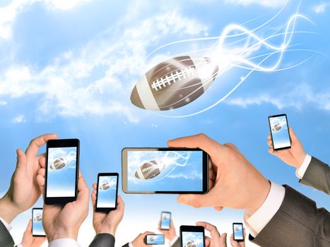 Hands holding smart phones and shoot video as falling American football. Sky with clouds on background
