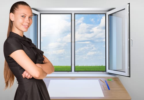 Beautiful businesswoman in dress smiling and looking at camera. Open window with green meadow and sky as backdrop