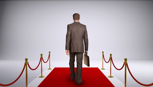 Businessman in suit holding briefcase and go forward on red carpet. Rear view. Business concept