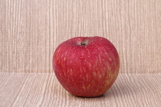 red apple on wooden background with some drops.