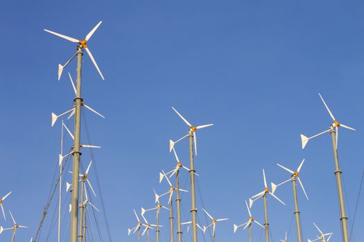Wind driven generators, turbines over blue sky