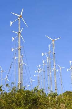 Wind driven generators, turbines over blue sky