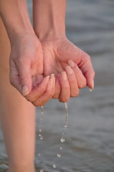 Photo shows a detail of the water drops in woman hands.