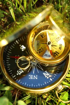 Two golden compasses on green grass