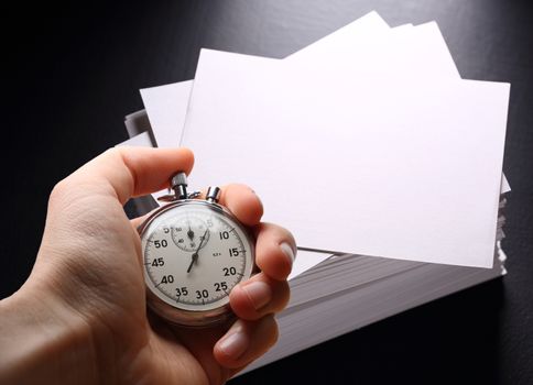 Paper cards on black and hand with stopwatch