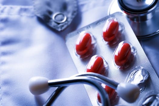 Stethoscope and pills and on doctor's smock