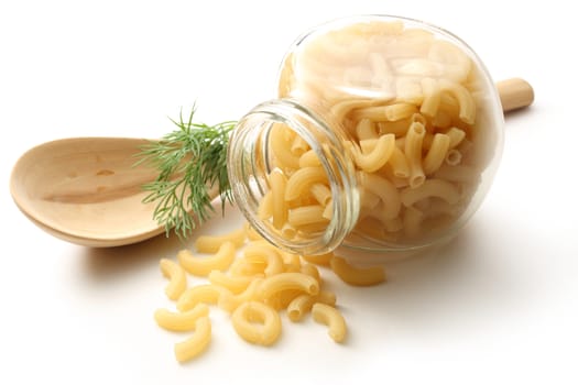 Short ribbed pasta tubes in jar and wooden spoon