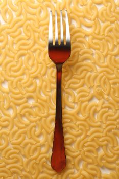 Short ribbed pasta tubes background with fork