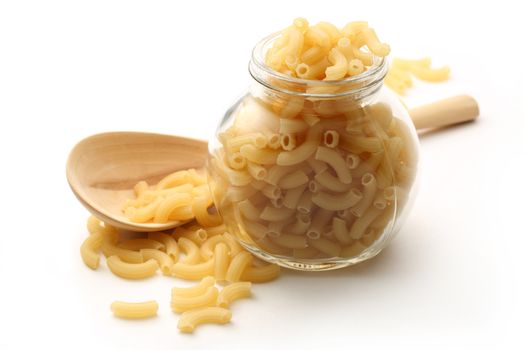 Short ribbed pasta tubes in jar and wooden spoon