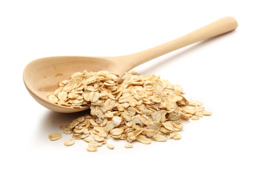 Heap of rolled oats with wooden spoon on white