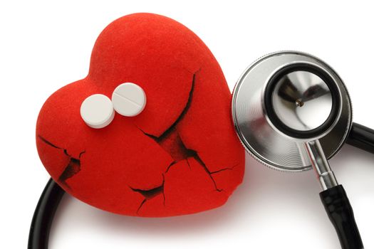 Red broken heart, stethoscope and pills on white