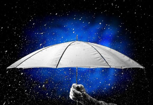 Umbrella under raindrops in hand