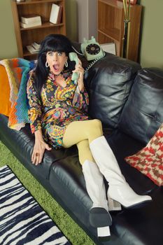 Amazed pretty woman on sofa holding telephone