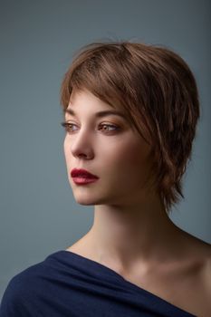 Side portrait of a young woman with short brown hair and brown glowing eyes