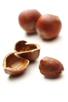 Whole and cracked hazelnuts on white