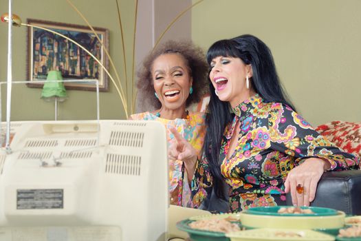 1960s style women laughing while watching television