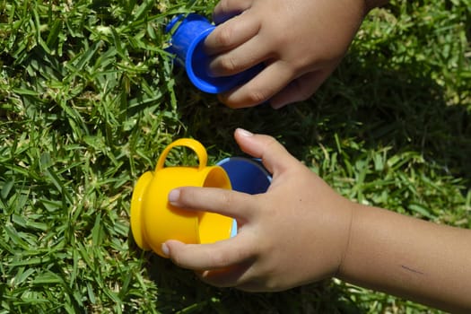 Hand of a child playing with colored plastic cups