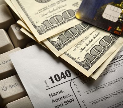 Computer keyboard, credit cards, tax form and dollars in cash
