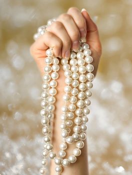 Pearl in the woman hand on sparkling background