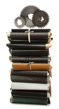 Steel cogwheels on stack of old paper folders