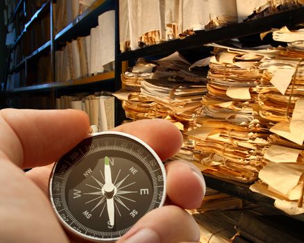 Hand with stopwatch, paper documents stacked in archive