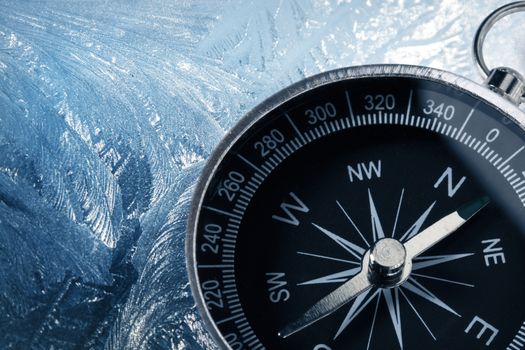 Black compass on icy background
