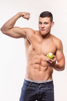 Muscular fitness man with apple showing biceps - studio shoot