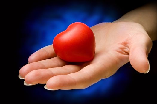 Heart in hand on black and blue background