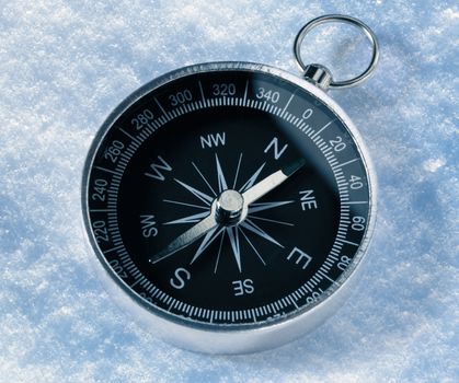 Black compass on snow background