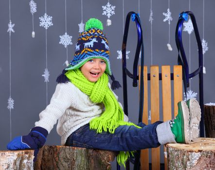 Winter Fashion. Portrait of adorable happy boy in winter hat, gloves and sweater in studio.