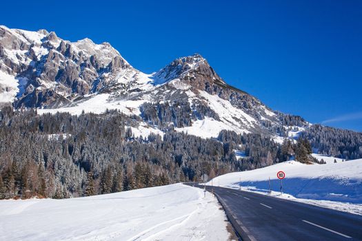 Panorama of winter in the Austrian alps mountain. Asphalt road among snow.