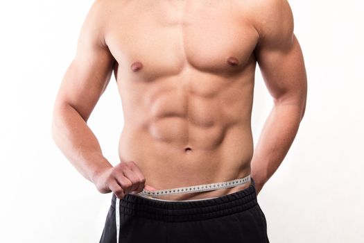 Muscular fitness man measuring his waist - studio shoot 