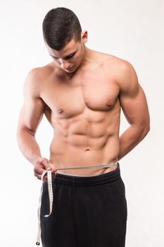 Muscular fitness man measuring his waist - studio shoot 