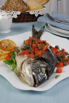 Baked Fish (Dorado) decorated with slices of peppers with capers