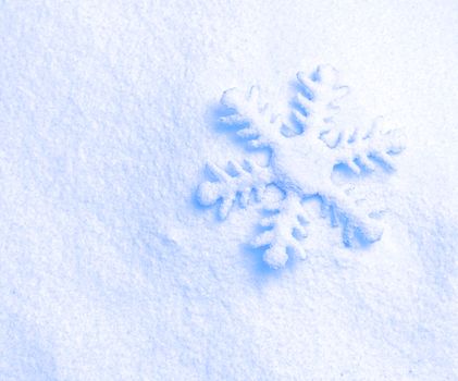 snowflake ornament against a background of snow