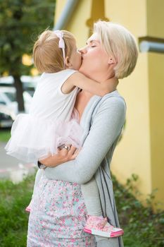 mother kissing her daughter in the park