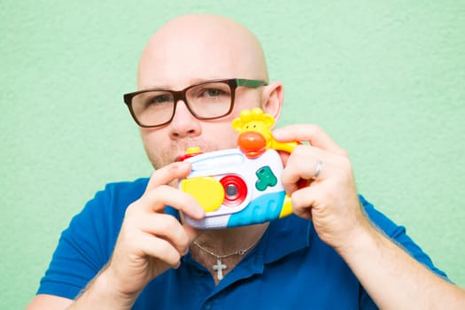 Young man taking photo with toy camera, focus on face