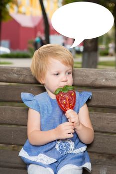 Beautiful little girl holding a big strawberry shaped lollipop