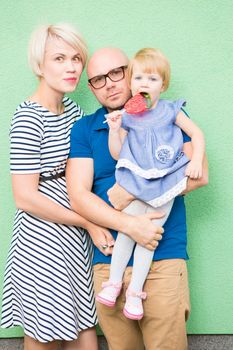 Happy mother, father and daughter on green background