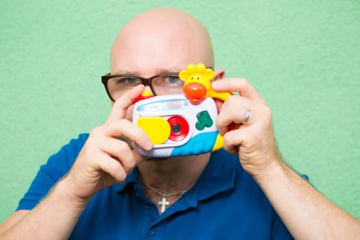 Young man taking photo with toy camera, focus on face