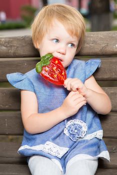 Beautiful little girl holding a big strawberry shaped lollipop