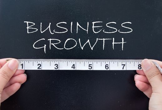 Hands holding a tape measuring the words business growth