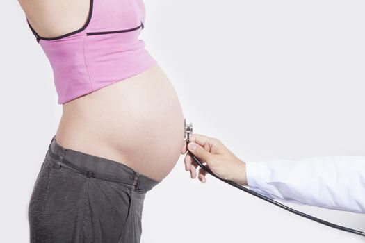 doctor hand with stethoscope on tummy of naked pregnant woman