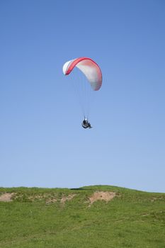 paraglider flying over green field in Asturias Spain