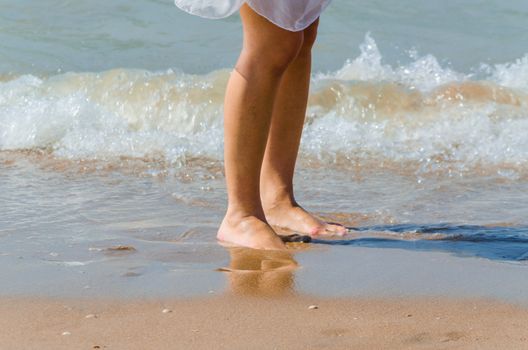 Feet of a young woman on the beach in the background of the sea.