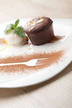 Warm dessert chocolate cake Fondant served on plate with ice-cream ball, almond chips, mint, icing, citron, cacao