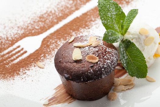 Warm dessert chocolate cake Fondant served on plate with ice-cream ball, almond chips, mint, icing, citron, cacao