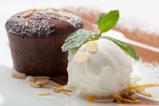 Warm dessert chocolate cake Fondant served on plate with ice-cream ball, almond chips, mint, icing, citron, cacao