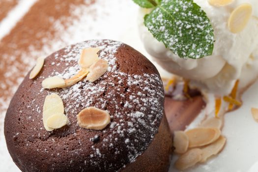 Warm dessert chocolate cake Fondant served on plate with ice-cream ball, almond chips, mint, icing, citron, cacao