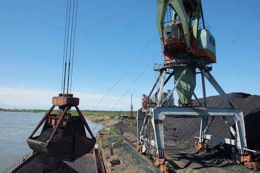 Crane loading coal to ship at Kolyma river port, Zyryanka, Yakutia region, Russia